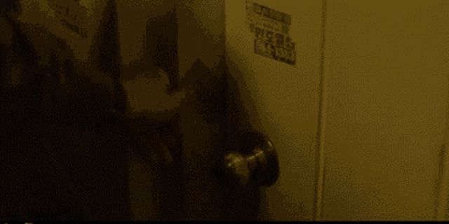 a person is opening a door with a sticker on the wall that says ' warning ' on it