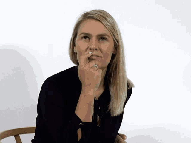 a woman is sitting in a chair with her finger in her nose .
