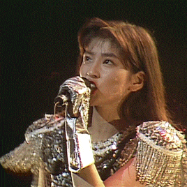 a woman singing into a microphone with a glove around her hand