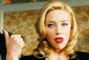 a blonde woman with red lipstick is giving a thumbs up sign .