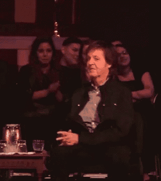 a man in a black jacket is sitting in front of a crowd of people