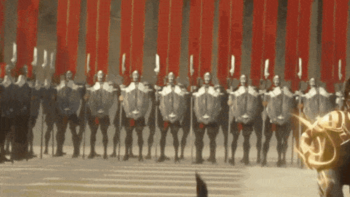a row of soldiers with shields and spears are standing in front of a red wall