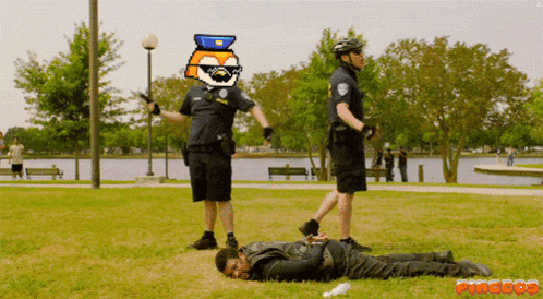 a man is laying on the grass with two police officers standing around