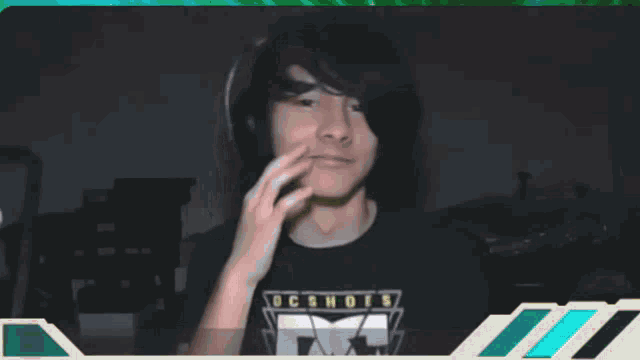 a man wearing headphones and a black shirt with the letter m on it is smiling
