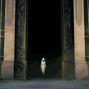 a woman in a white dress stands in front of a large door that says ' i ' on it