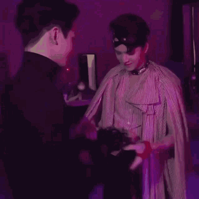 a couple of men are standing next to each other in a dark room .