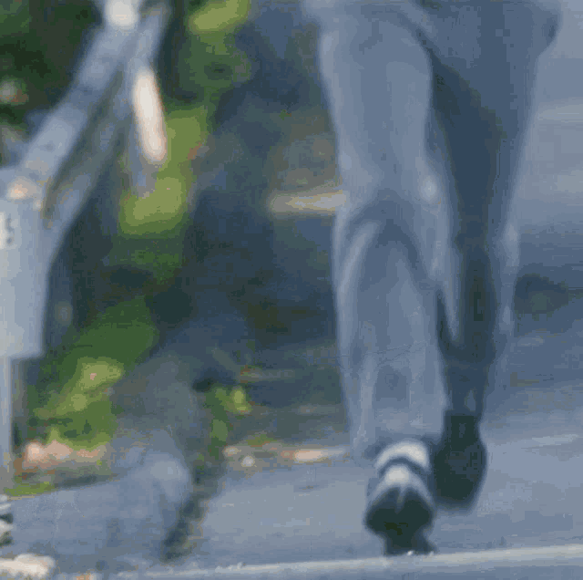 a man in a grey shirt and blue pants is running down a street