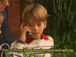 a young boy is talking on a cell phone while a man looks on .