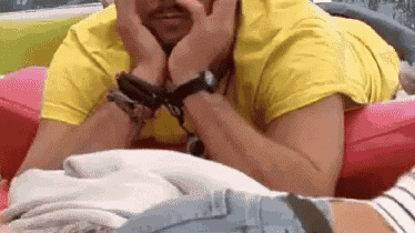 a man is laying on a couch with his hands on his face .