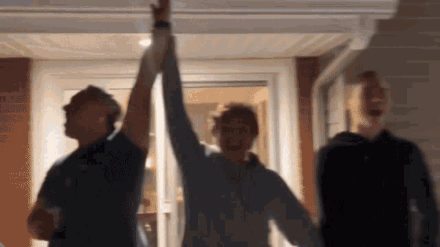 a group of people are standing in front of a house giving each other high fives