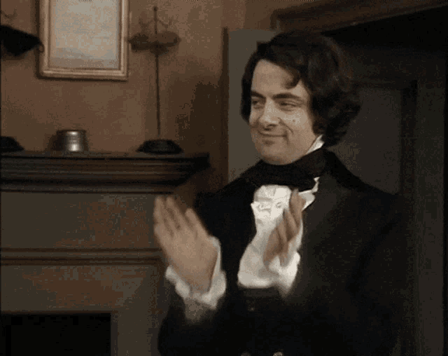 a man in a suit and bow tie is clapping his hands