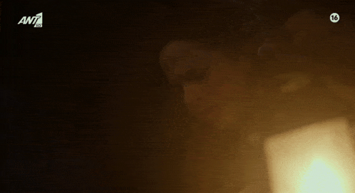 a woman is sitting in front of a lamp in a dark room with the number 16 on the bottom of the screen .