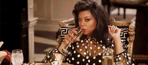 a woman in a polka dot dress is drinking a glass of champagne .