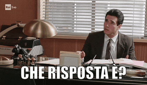 a man in a suit and tie sits at a desk with the words che risponda e