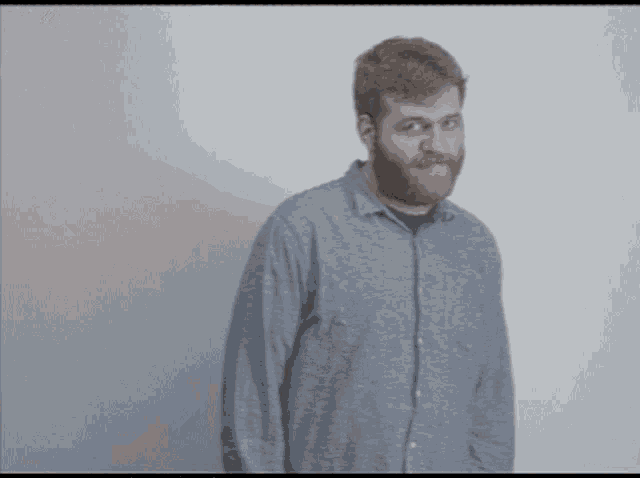 a man with a beard is standing in front of a wall