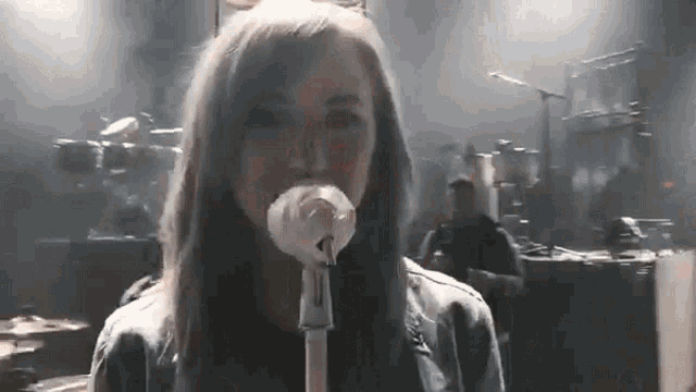 a woman is singing into a microphone on a stage in front of a crowd .