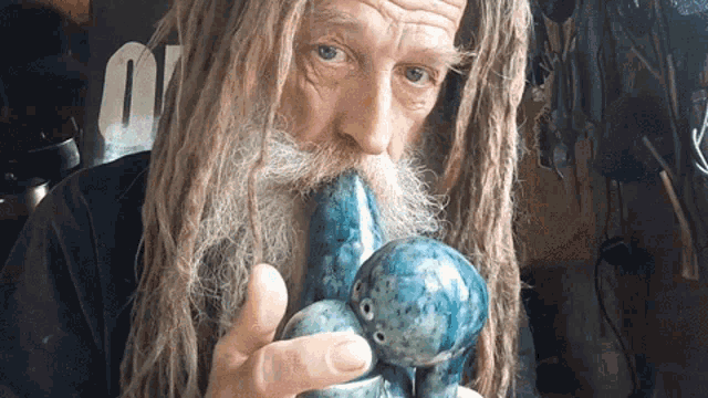 a man with dreadlocks and a beard smoking a blue pipe
