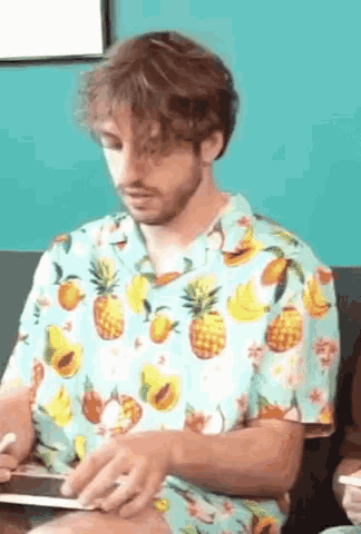 a man wearing a blue shirt with pineapples and bananas on it