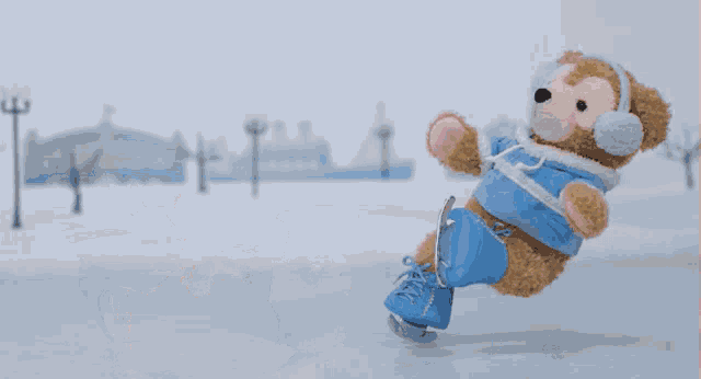 a teddy bear wearing ear muffs and a blue jacket is laying on the ground