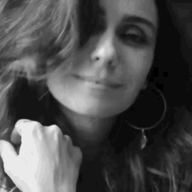 a woman wearing hoop earrings is smiling in a black and white photo