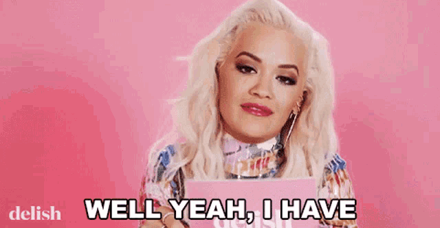 a woman with blonde hair is holding a pink box and saying well yeah , i have .