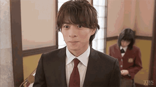 a man in a suit and tie is standing in front of a woman in a red jacket ..