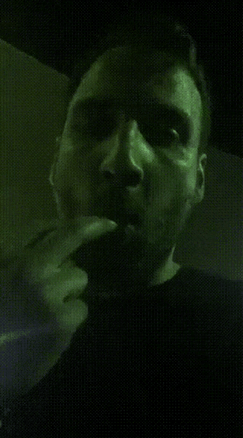 a man with a beard smoking a cigarette in a dark room