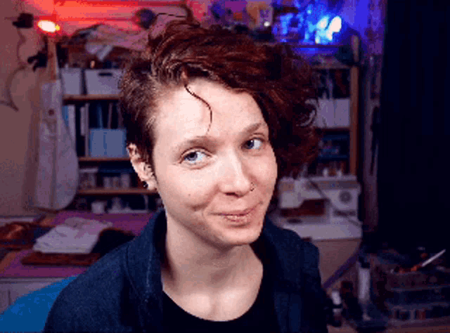 a woman with red hair and a nose ring smiles