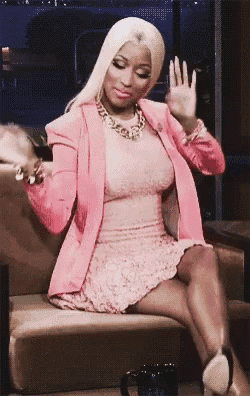 a woman in a pink dress is sitting on a couch waving