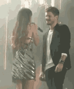 a man and a woman are standing on a stage looking at each other .