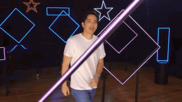 a man in a white shirt is standing in front of a neon sign that says i love you