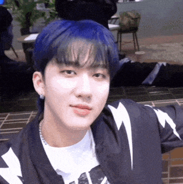 a young man with blue hair and a lightning bolt jacket