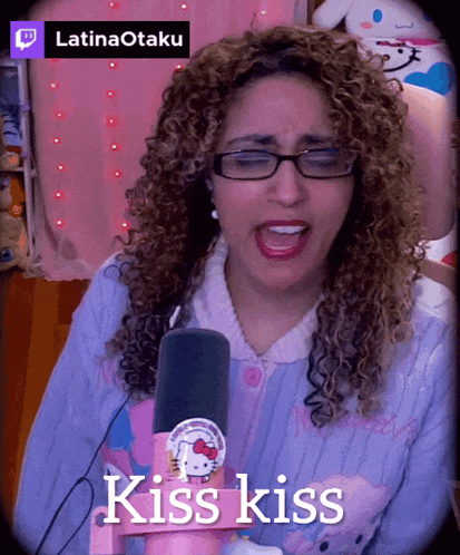 a woman with curly hair singing into a microphone with the words kiss kiss above her