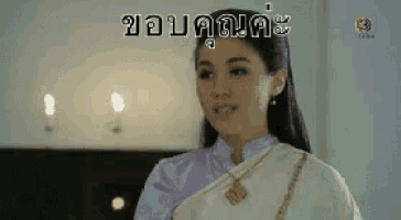 a woman in a purple and white dress is standing in front of a candle .