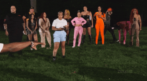 a group of women are standing in a line with one wearing a pink outfit