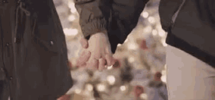 a close up of two people holding hands in front of a christmas tree .