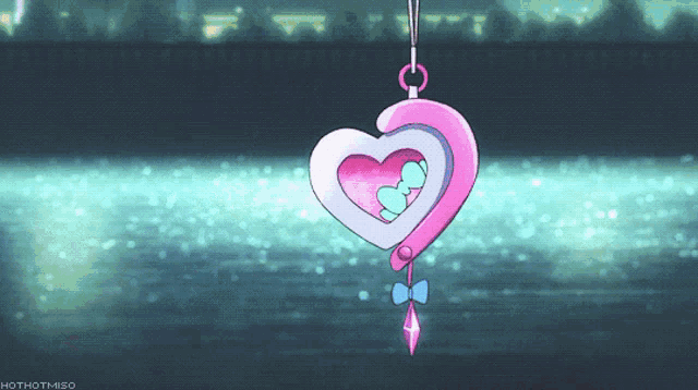 a pink heart shaped pendant with a blue bow is hanging from a string