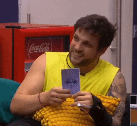 a man is holding a playing card in front of a coca cola machine .