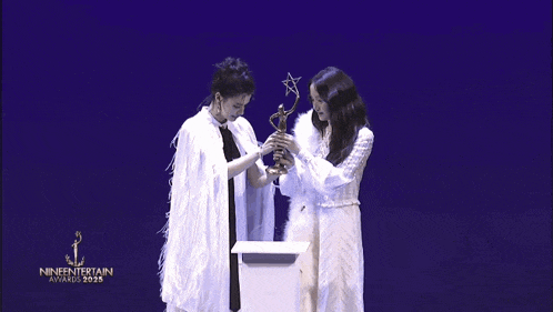two women holding a trophy that says nineentertainment awards on it