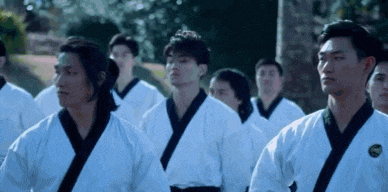 a group of young men in karate uniforms are standing in a row .