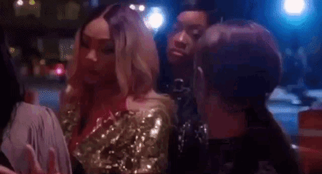 a group of women are standing next to each other in a dark room talking into microphones .