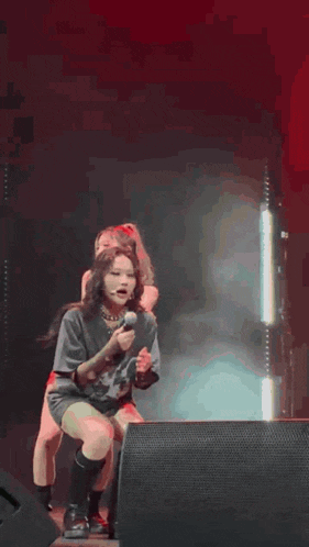 a woman is kneeling down on a stage while another woman is standing behind her .