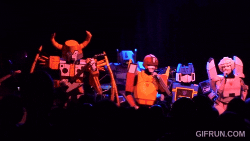 a group of transformers are performing on a stage in front of a crowd .