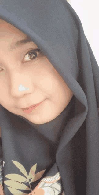 a woman wearing a blue hijab and a floral shirt