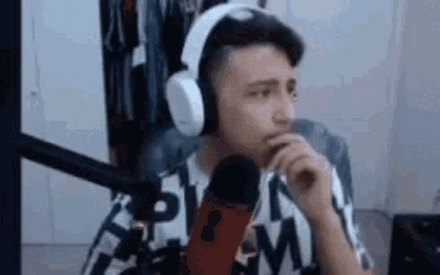 a man wearing headphones is sitting in front of a microphone and talking into it .