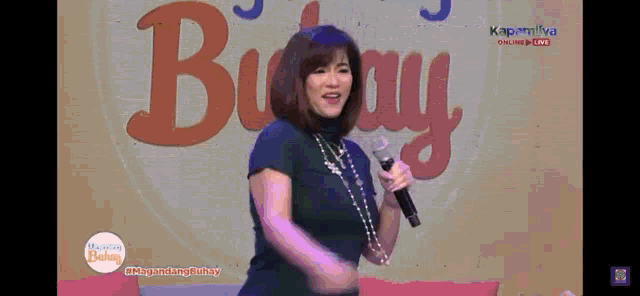 a woman sings into a microphone in front of a sign that says buhay