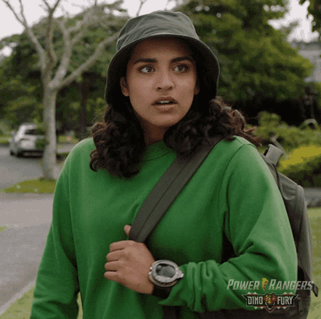 a woman wearing a green power rangers sweatshirt and hat