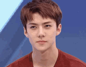 a close up of a young man 's face with a red shirt on