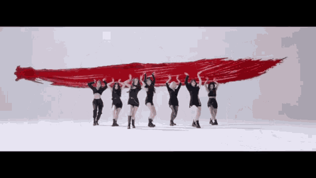 a group of women are holding up a large red brush