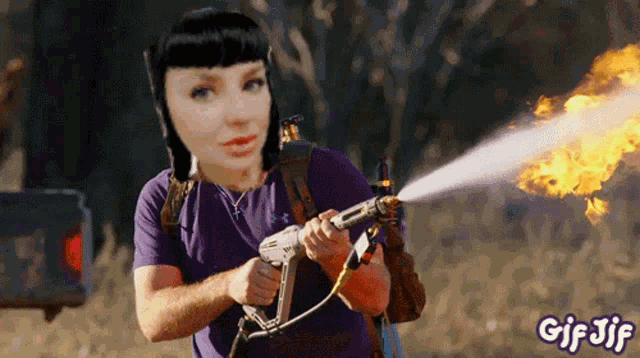 a woman in a purple shirt is holding a gun with fire coming out of it and the words gif jif below her